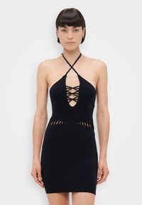 Abito nero a halter con scollatura a V profonda e spalline incrociate. Presenta dettagli a taglio in vita e una silhouette aderente. Tessuto liscio.