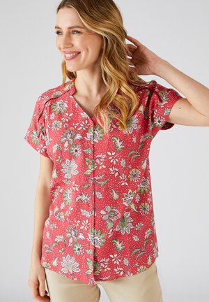 Red floral blouse with short sleeves, featuring a V-neckline, button front, and a pattern of white and green flowers on a dotted background.