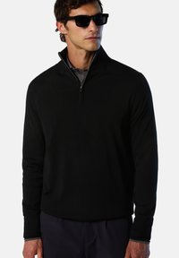 Pullover in pile nero con colletto alto e zip, caratterizzato da maniche lunghe, una consistenza morbida e sottili dettagli interni a contrasto.