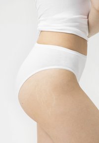 Sous-vêtements en coton blanc à taille haute, texture lisse et taille élastique subtile, montrant une vue de profil sur un fond clair.
