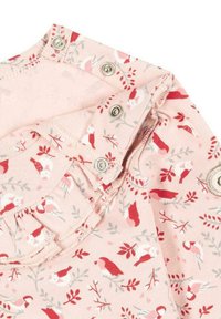 Tissu en coton rose avec un motif floral et d'oiseaux. Le vêtement possède des boutons-pression au niveau du col et un bord festonné.