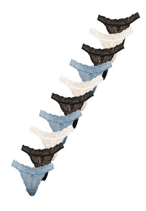 Kobieta ubrana w biały crop top z wiązaniem na szyi i czarne koronkowe stringi, stojąca na jednolitym jasnoszarym tle.