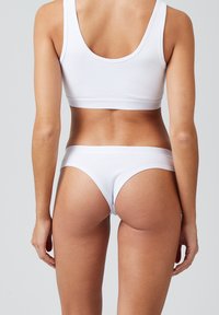 Witte katoenen sportbeha en string, naadloos ontwerp, zachte textuur, brede banden, low-rise taille, minimalistische details.