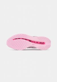 Semelle de chaussure de course Nike Zoom rose avec un motif de grip texturé et le texte noir "ZOOM" visible à travers la fenêtre de la semelle intermédiaire.