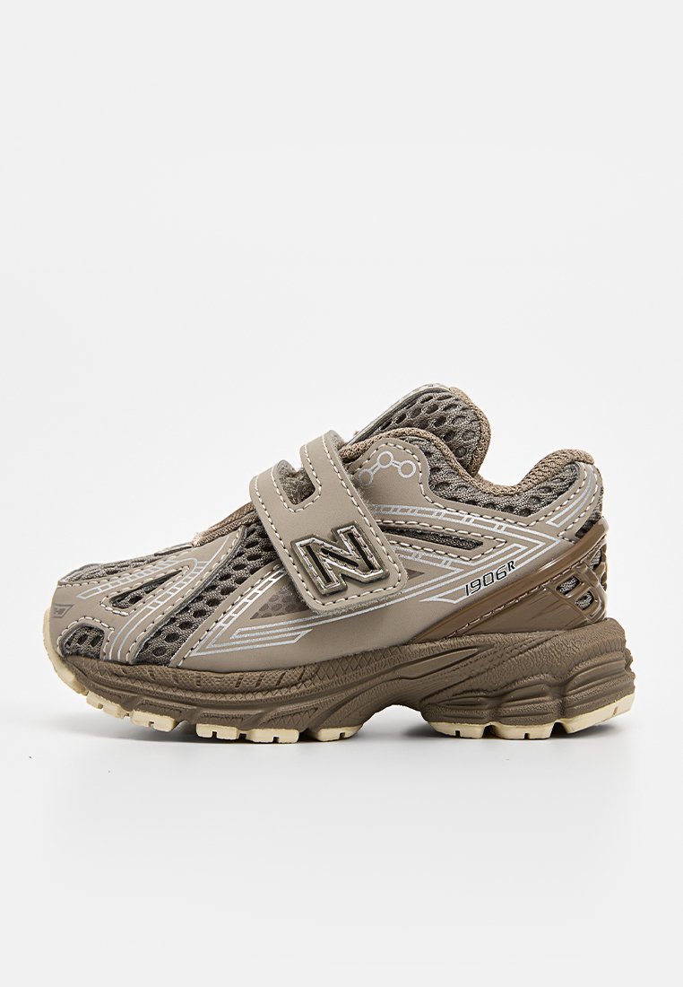 Chaussure de sport tan avec panneaux en maille, col rembourré, sangle ajustable et semelle en caoutchouc légère. Présente un logo sur le côté.