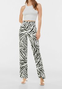 Kalhoty s vysokým pasem s potiskem zebry v černobílé barvě, s širokými nohavicemi a lehkým materiálem, spárovány s přiléhavým bílým crop topem.