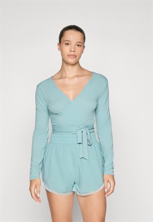 Haut enveloppant bleu clair à manches longues et décolleté en V ; associé à un short assorti avec un taille élastique et un détail de nœud.