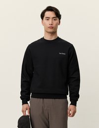 Melna kokvilnas sporta krekla ar apaļu kakla izgriezumu un garām piedurknēm, uz krūtīm ir neliels balts logo "Les Deux". Gluda tekstūra, brīvs piegriezums.