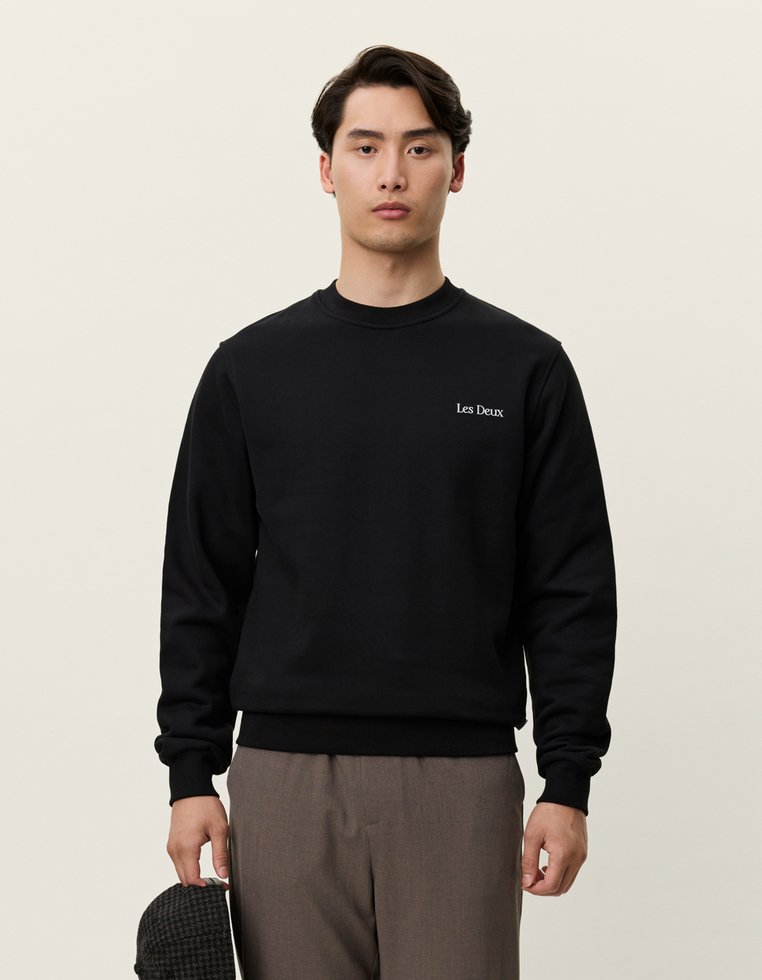 Melna kokvilnas sporta krekla ar apaļu kakla izgriezumu un garām piedurknēm, uz krūtīm ir neliels balts logo "Les Deux". Gluda tekstūra, brīvs piegriezums.