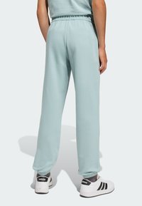 Svetlo modré tepláky v voľnom strihu s elastickým pásom a manžetami. Skombinované s bielymi teniskami s čiernymi akcentmi.