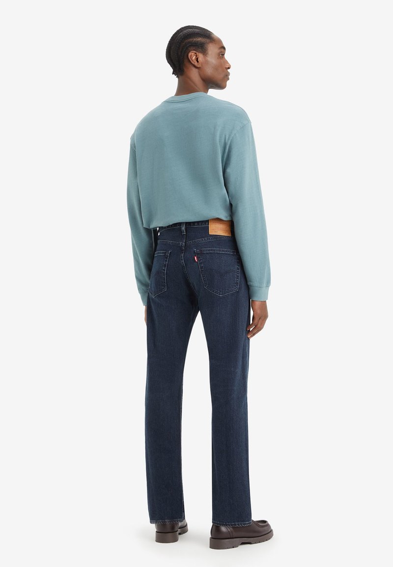 Donkerblauwe jeans met een rechte pasvorm en achterzakken. Gepaard met een lichtblauw langslouchshirt, de stof heeft een zachte textuur. Bruin leren label zichtbaar.
