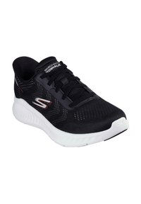 Zapatilla deportiva negra con parte superior de malla, tejido texturizado, suela blanca, cordones y logo de Skechers en el lateral. Ideal para caminar y uso casual.