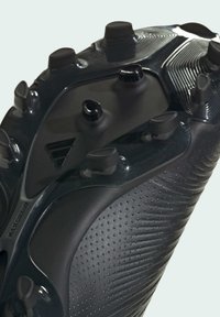 Botas de fútbol negras con parte superior sintética texturizada, patrón de agarre elevado y múltiples tacos moldeados en la suela para tracción en diversas superficies.