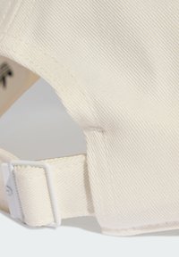 Bílá baseballová kšiltovka s texturovanou tkaninou, s křivým kšiltem a nastavitelným popruhem s plastovou sponou na zadní straně.