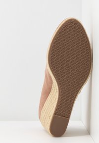 Ruskea mokkainen kenkä, jossa on juutilla päällystetty kiilakorko ja kuvioitu kumipohja. Korko kapenee lempeästi taaksepäin.