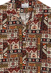 Camicia a maniche corte con un complesso motivo geometrico in rosso, nero e giallo su uno sfondo crema; vestibilità rilassata con tasca sul petto.