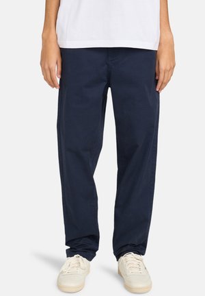 Navy blue, lightweight cotton pants with a relaxed fit. Features side pockets and cuffed hems, worn with white sneakers.