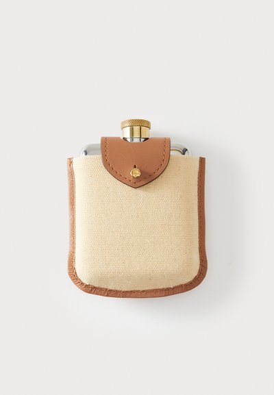 Nierdzewna piersiówka w beżowym pokrowcu z tkaniny płóciennej z brązowymi skórzanymi akcentami, wyposażona w złotą zakrętkę i zatrzask.