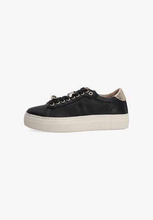 Black leather low-top sneaker with thick white sole, gold eyelets, decorative bee charms on laces, and metallic gold heel accent.