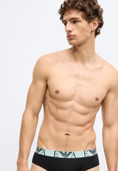 Cuecas masculinas pretas com cintura elástica azul clara que apresenta um logótipo. O tecido parece macio e o design é justo ao corpo.