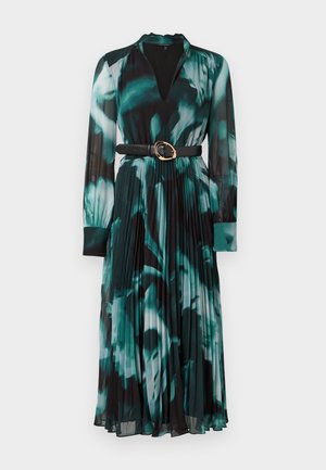 Robe à manches longues avec un imprimé floral vert et noir, présentant un décolleté en V, une jupe plissée, et une ceinture noire avec une boucle en or.