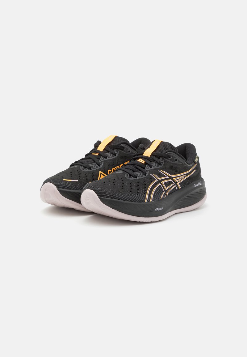 Baskets de sport noires avec un dessus en maille, accents orange et semelle texturée. Dotées d'un bout arrondi et d'un système de laçage pour un ajustement sécurisé.