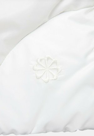 Tissu blanc rembourré avec un subtil éclat, comportant un motif floral brodé de couleur assortie près du bord. Texture lisse.