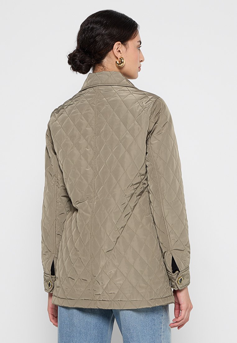 Gepolsterte, khakifarbene Jacke mit entspannter Passform. Mit Kragen, knöpfbaren Manschetten, seitlichen Schlitzen und gestepptem Rautenmuster. Weiche Textur.