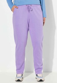 Lila mjukisbyxor med dragsko i midjan, sidofickor och en mjuk textur, kombinerat med chunky sneakers i flera färger.