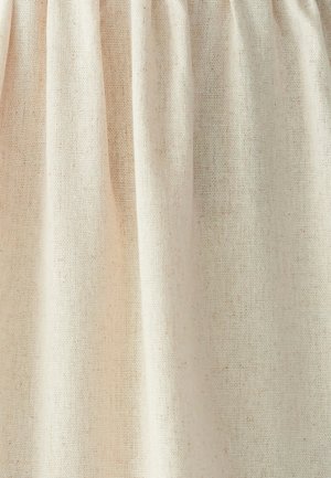 Beige loosely woven fabric with visible threads and soft folds creating vertical shadows and texture.