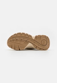 Suola della scarpa con un design del battistrada pronunciato, realizzata in un robusto materiale gommoso marrone. Tacco arrotondato e superficie texturizzata per una presa migliore.