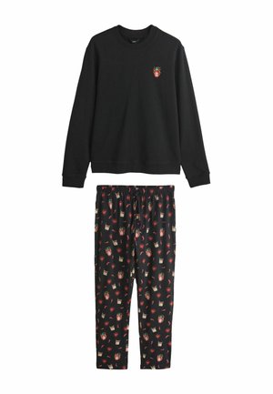 Sort langærmet top med lille farverig hot sauce-flaske og flammer grafik, kombineret med sorte bukser med mønster af hot sauce-flasker, hjerter og chilipeber.