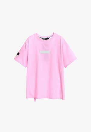 Camiseta de algodón rosa con mangas cortas. Presenta una etiqueta blanca rectangular en el frente y una pequeña etiqueta rosa en el dobladillo. Cuello redondo.