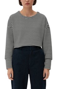 Svart- och vitrandig kort sweatshirt med vid halsringning och långa ärmar, ihop med mörka högmidjade byxor. Texturerad tyg.