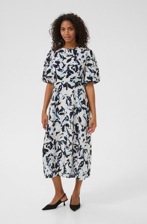 Floral-patterned midi dress in white, navy, and light blue. Features puff sleeves, a rounded neckline, and a fitted waist. Black heeled shoes.