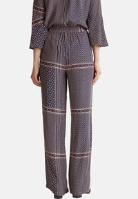 Marina-mönstrade vida byxor med geometriska mönster i röd och vit. Har ett elastiskt midjeband och en mjuk tygtextur för komfort.