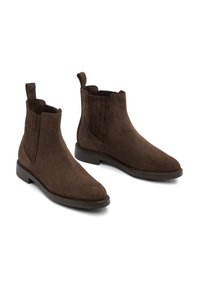 Par de botas Chelsea de ante marrón oscuro con paneles laterales elásticos y tiradores en fondo blanco.