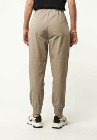 Lichte, beige joggingbroeken met een elastische tailleband en boorden, voorzien van een subtiel textuurpatroon en een losse pasvorm.