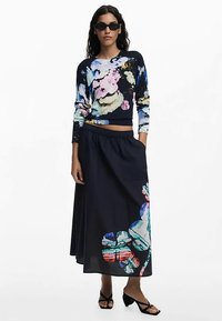 Marineblauer Blumenpullover mit lebendigen, mehrfarbigen abstrakten Mustern und einem passenden langen, fließenden Rock mit großen Blumenmustern.