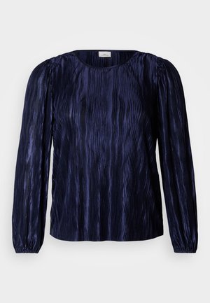 Temno modra bluza z dolgimi rokavi z navpično plisirano teksturo, okrogel izrez in elastičnimi manšetami. Svilnata tkanina odbija svetlobo.