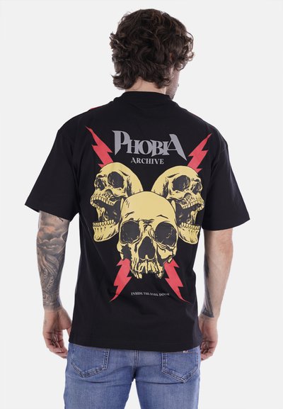 Maglietta nera in cotone con una grafica vivace di un teschio giallo con fulmini rossi e la scritta "PHOBIA ARCHIVE" sulla parte posteriore.