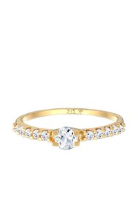 Anello d'oro con una pietra centrale a taglio rotondo e molteplici piccole pietre trasparenti lungo la fascia, creando un effetto stratificato delicato.