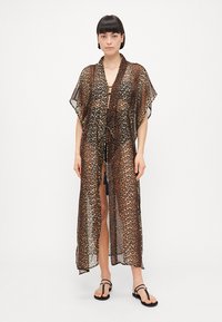 Prozirni kimono sa leopard uzorkom, širokim rukavima, vezanjem na kravatu i dugom dužinom. Boje uključuju bež, smeđu i crnu u prozirnom materijalu.