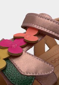 Δερμάτινο σανδάλι σε μπρονζέ απόχρωση με πολύχρωμες ανθικές λεπτομέρειες σε ροζ, πορτοκαλί και κίτρινο χρώμα· ανάγλυφη πράσινη λεπτομέρεια φύλλου· ρυθμιζόμενα λουριά.