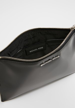 Sort Michael Kors håndleds taske med sølv lynlås åben for at vise det mærkede indvendige foer og læder logo patch indeni.