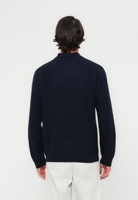 Pulover marin cu guler, cu manșete și tiv cu dungi. Fabricat dintr-un material moale, are un design fără cusături la spate și o croială lejeră.