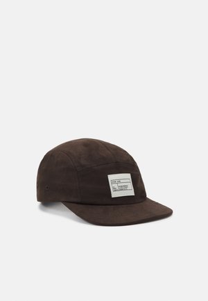 Brown canvas cap with a flat brim, featuring a white rectangular patch on the front and stitching details along the seams.