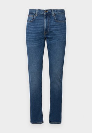 Jean en denim bleu foncé avec une coupe droite, doté d'une fermeture éclair, de cinq poches et d'un léger délavage à l'avant. Des accents cousus sont présents.
