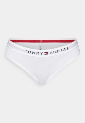 Hvide bomuldsbikini-trusser med en elastisk talje med røde striber. Har "TOMMY HILFIGER" logoet trykt på forsiden. Glat tekstur.