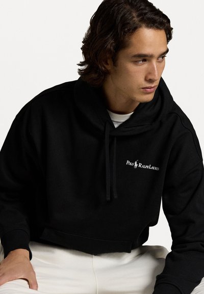 Zwarte cropped hoodie met een drawstring, voorzien van een wit geborduurd logo op de borst. Gemaakt van zachte stof met een relaxte fit.